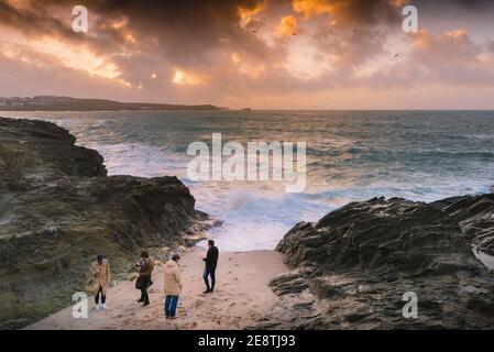 Coucher de soleil d'or avec quatre jeunes hommes se trouvant sur la plage dans une petite crique de Little Fistral à Newquay en Cornouailles. Banque D'Images