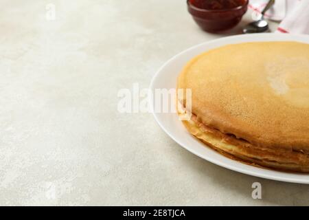 Concept de petit déjeuner avec assiette de crêpes fines et confiture sur fond blanc texturé Banque D'Images