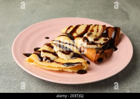Assiette de crêpes avec sauce au chocolat et tranches de banane arrière-plan gris Banque D'Images