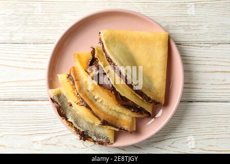 Plaque de crêpes avec pâte de chocolat sur fond de bois blanc Banque D'Images