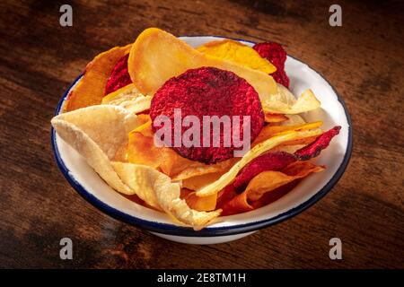 Chips de légumes dans un bol, un en-cas végétalien sain sur fond de bois rustique foncé Banque D'Images