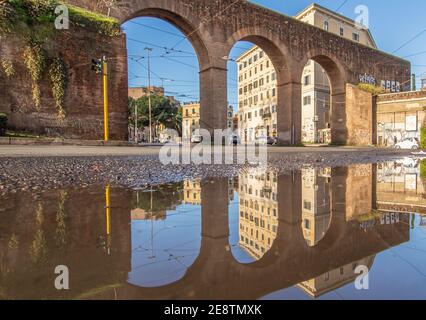 Les fréquentes averses de pluie créent des piscines dans lesquelles la merveilleuse vieille ville de Rome se reflète comme dans un miroir. Ici en particulier la Piazza di Porta Maggiore Banque D'Images