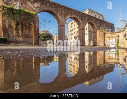 Les fréquentes averses de pluie créent des piscines dans lesquelles la merveilleuse vieille ville de Rome se reflète comme dans un miroir. Ici en particulier la Piazza di Porta Maggiore Banque D'Images