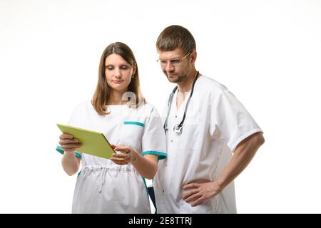 Médecin et infirmière discutant des tests du patient, en regardant attentivement l'écran d'un ordinateur tablette Banque D'Images