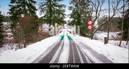 Route enneigée et pont étroit à Butgenbach, Ardennes, Belgique. Banque D'Images