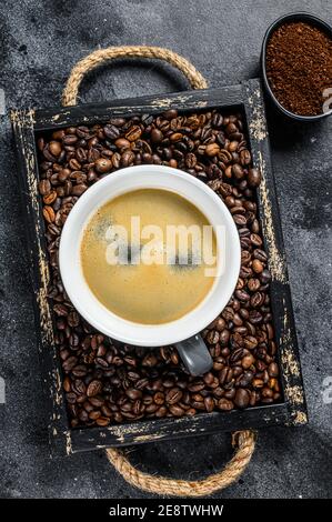 Tasse de café et haricots dans un ancien plateau en bois fond noir. Vue de dessus Banque D'Images