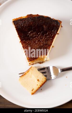 Partie du traditionnel basque brûlé cheesecake sur une assiette prêt à manger Banque D'Images