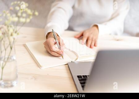 Une femme écrit dans un ordinateur portable sur un bureau avec un ordinateur portable Banque D'Images