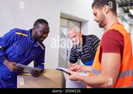 Trois travailleurs qui vérifient une livraison de marchandises avec la liste de contrôle presse-papiers Banque D'Images