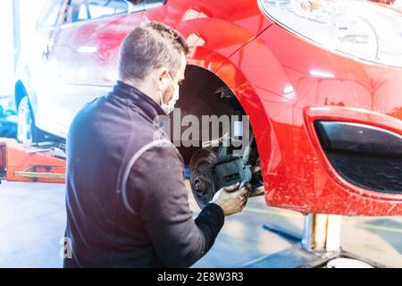 mécanicien répare la suspension de voiture. Concentrez-vous sur les mains. COVID 19 Banque D'Images