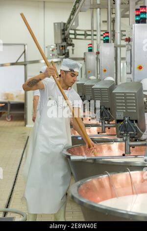 Un homme remuant le lait dans une cuve doublée de cuivre parmigiano reggiano de fromage Parmessan dans une usine de Bologne Italie Banque D'Images