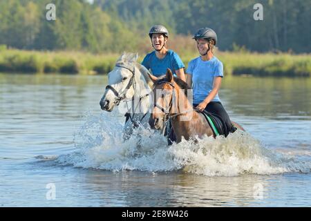 Deux cavaliers sur des poneys dans un lac Banque D'Images