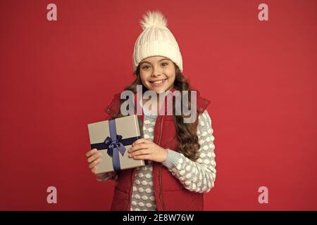 Vrai bonheur. Faites des choses agréables. Joyeux enfant en hiver fond rouge. Nouvelle année à venir. Petit coffret cadeau pour enfant. Bonne enfance. Cadeaux de Noël souvenirs. Préparez-vous pour les vacances d'hiver. Banque D'Images