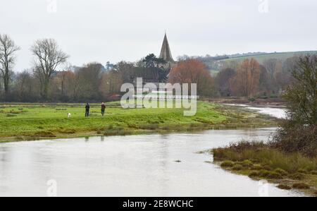 Brighton Royaume-Uni 1er février 2021 - marcheurs pour chiens au bord de la rivière Cuckmere à Alfriston près de Seaford dans East Sussex par une journée sombre et nuageux dans le Sud-est . Les niveaux d'eau de la rivière sont élevés avec les champs environnants étant inondés après des semaines de pluie durables à travers les mois d'hiver en Grande-Bretagne : crédit Simon Dack / Alamy Live News Banque D'Images