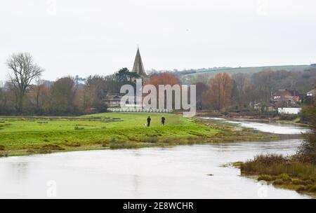 Brighton Royaume-Uni 1er février 2021 - marcheurs pour chiens au bord de la rivière Cuckmere à Alfriston près de Seaford dans East Sussex par une journée sombre et nuageux dans le Sud-est . Les niveaux d'eau de la rivière sont élevés avec les champs environnants étant inondés après des semaines de pluie durables à travers les mois d'hiver en Grande-Bretagne : crédit Simon Dack / Alamy Live News Banque D'Images
