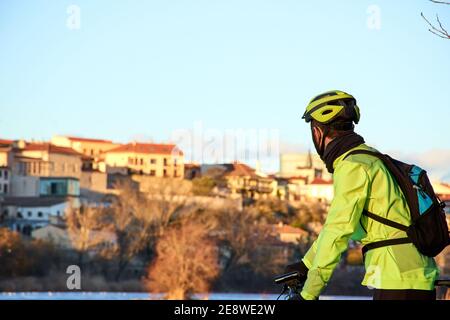 Roue d'un VTT sur la rive de la rivière. Mountain bike rider se reposant, regardant un coucher de soleil de la ville. Vue horizontale Banque D'Images