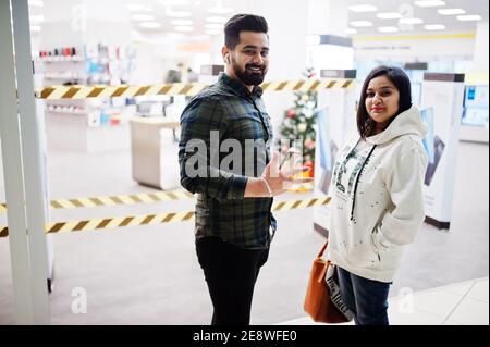 Un couple indien prend l'argent du portefeuille au centre commercial. Banque D'Images