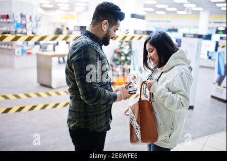 Un couple indien prend l'argent du portefeuille au centre commercial. Banque D'Images