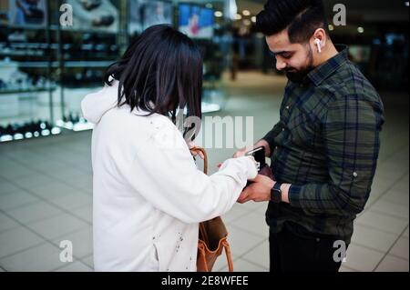 Un couple indien prend l'argent du portefeuille au centre commercial. Banque D'Images