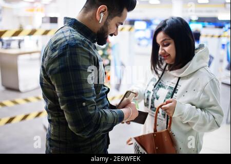 Un couple indien prend l'argent du portefeuille au centre commercial. Banque D'Images