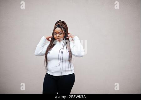 Femme afro-américaine glamour en chandail blanc à col roulé pose dans la rue. Banque D'Images