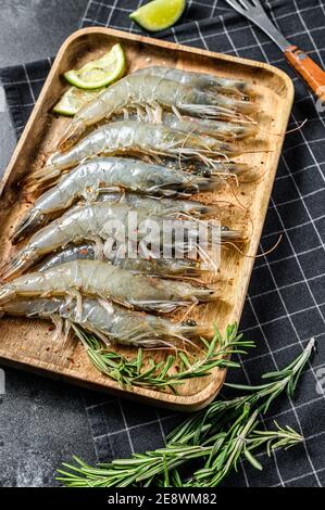 Crevettes tigrées fraîches entières, crevettes sur un plateau en bois fond noir. Vue de dessus Banque D'Images