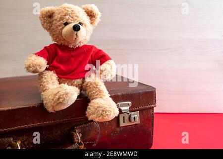 Voyage avec les enfants, concept enfant abandonné. Adorable peluche sur une valise vintage. Bagages rétro en cuir dans une chambre enfant Banque D'Images