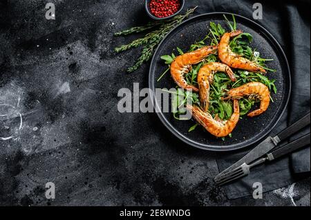 Crevettes géantes grillées, crevettes, arugula et épices. Arrière-plan noir. Vue de dessus. Copier l'espace Banque D'Images