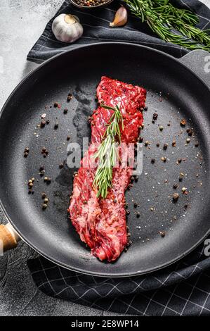 Steak de bœuf marbré cru, filet dans une casserole avec ingrédients pour la cuisson. Arrière-plan gris. Vue de dessus Banque D'Images