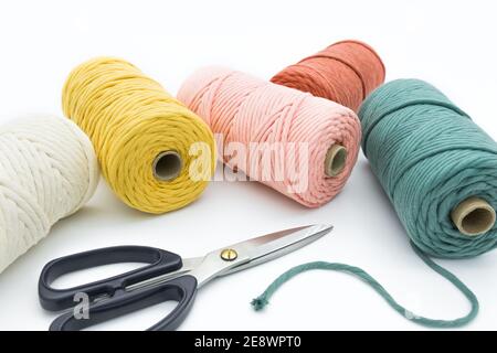 Vue rapprochée des cordons et ciseaux en coton à une rangée de couleurs pour les artisanes de macrame. Banque D'Images