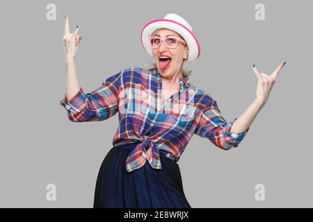 Portrait de crazy funny man moderne et élégant dans un style décontracté avec chapeau et lunettes debout, criant et looking at camera with rock signe. Banque D'Images