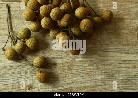 Fruits tropicaux longanés en branche sur une table en bois Banque D'Images