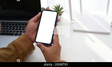 Vue rapprochée de l'homme utilisant un smartphone et assis devant le routeur sans fil au bureau à domicile. Banque D'Images