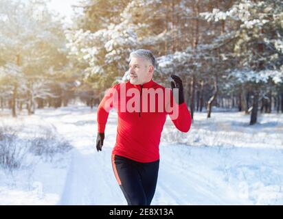 Concept de course par temps froid. Faites du jogging avec des vêtements de sport dans un parc hivernal enneigé. Entraînement saisonnier Banque D'Images