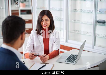 Une femme optométriste montrant les lunettes à son client Banque D'Images