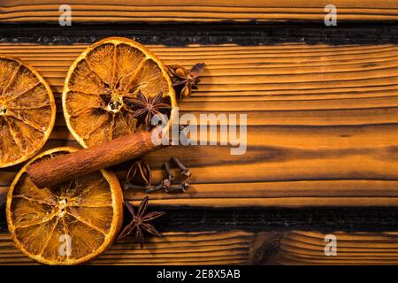 Épices de Noël aromatiques d'hiver sur fond de bois. Bâton de cannelle, clou de girofle, anis étoilé, tranches d'orange séchées espace vide pour le texte. Banque D'Images