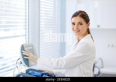 femme médecin boutons-poussoirs sur l'équipement médical, aime travailler à l'hôpital, regarder la caméra sourire . utiliser des équipements modernes pour le traitement en clinique. m Banque D'Images