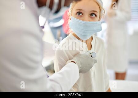 un homme africain, médecin vérifiant le rythme cardiaque d'une jeune fille à l'aide d'un stéthoscope, dans la chambre d'hôpital. portrait en gros plan de l'enfant regardant un médecin Banque D'Images