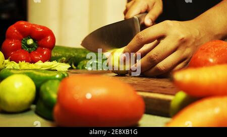 Femme coupant un citron et des légumes frais sur le hacher carte Banque D'Images