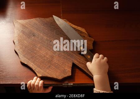 L'enfant tire un couteau de la table, danger. L'enfant peut couper, les dangers à la maison des enfants. Une petite fille d'un an avec un couteau. Banque D'Images