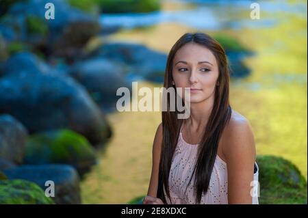 Une jeune femme pose le long des rives d'une petite rivière. Banque D'Images