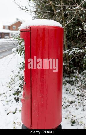 Gros plan de la boîte aux lettres royale rouge vif britannique à le bord de la route est recouvert de neige par temps froid Banque D'Images