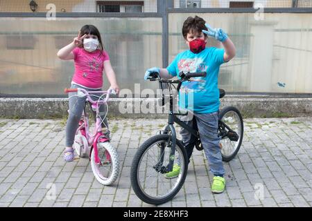 Campobasso, région de Molise, Italie: Deux enfants font le geste 'tout va bien' tout en jouant avec leurs vélos pendant les jours d'émergence du coronavirus Banque D'Images