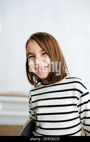 Petite fille souriant avec ses gencives et ses petites dents de bébé. Tenir la planche à roulettes. Banque D'Images