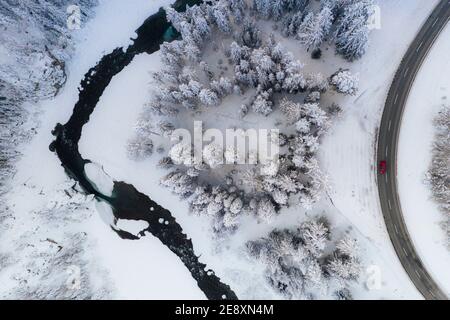 Voiture roulant sur des virages de route de montagne dans les bois enneigés d'en haut, Engadine, Suisse Banque D'Images