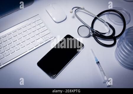 Bureau en chirurgie de médecins avec smartphone ordinateur clavier seringue et stéthoscope Banque D'Images