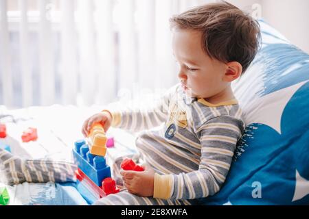 Mignon bébé tout-petit jouant bâtiment avec apprentissage jouets blocs d'empilage à la maison. Éducation de jeune âge. Développement des compétences motrices et du cerveau des mains des enfants. Banque D'Images