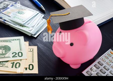 Économies pour l'université et le concept d'éducation. Banc de porc rose avec remise des diplômes et argent. Banque D'Images