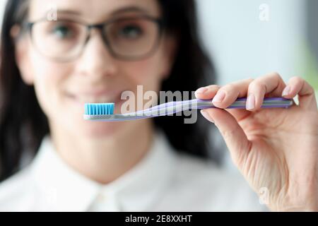 Jeune femme avec verres tenant la brosse à dents dans la salle de bains Banque D'Images