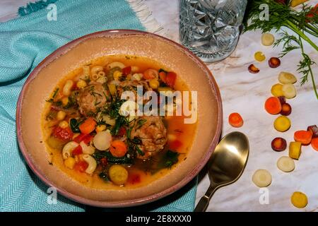 Soupe italienne de mariage avec boulettes de viande, pâtes aux carottes multicolores, petits pois chiches et épinards Banque D'Images